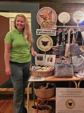 Kvinne i grøn genser ved stativ med vesker 