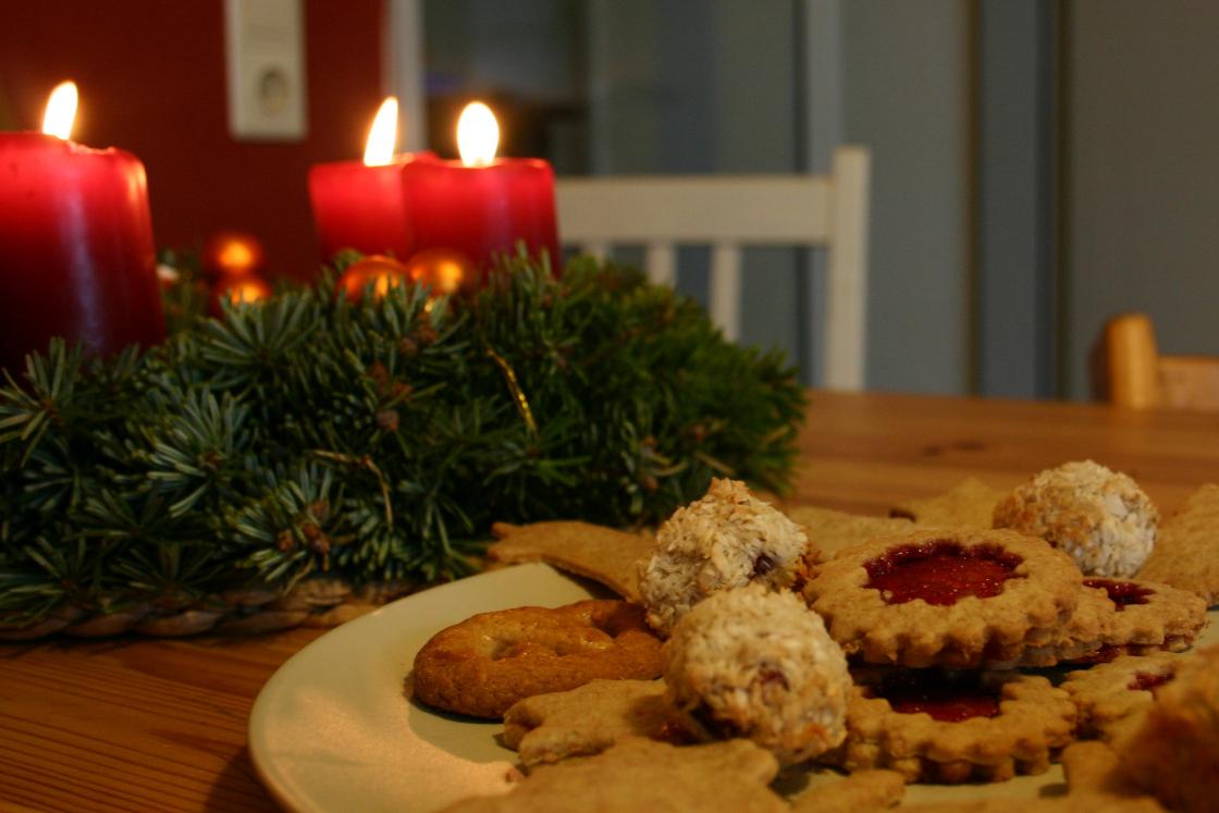 Kveikt adventskrans og fat med pepperkaker og andre småkaker