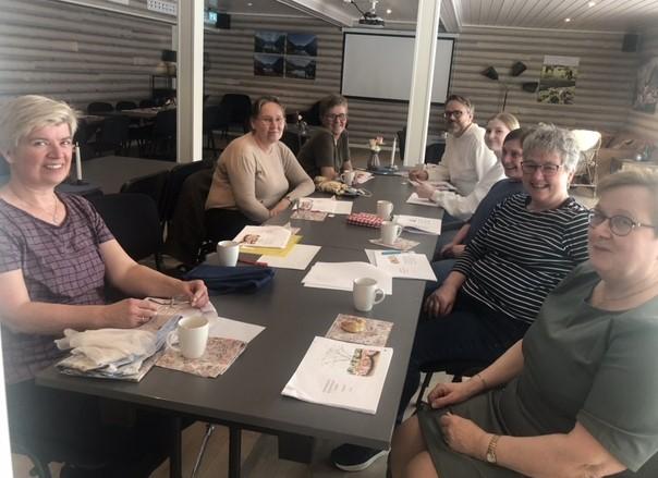 Kursdeltakarane samla rundt bordet og studerer oppskriftsheftet