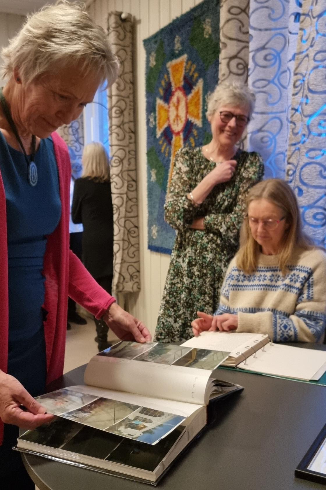 Tre kvinner ser på fotoalbum