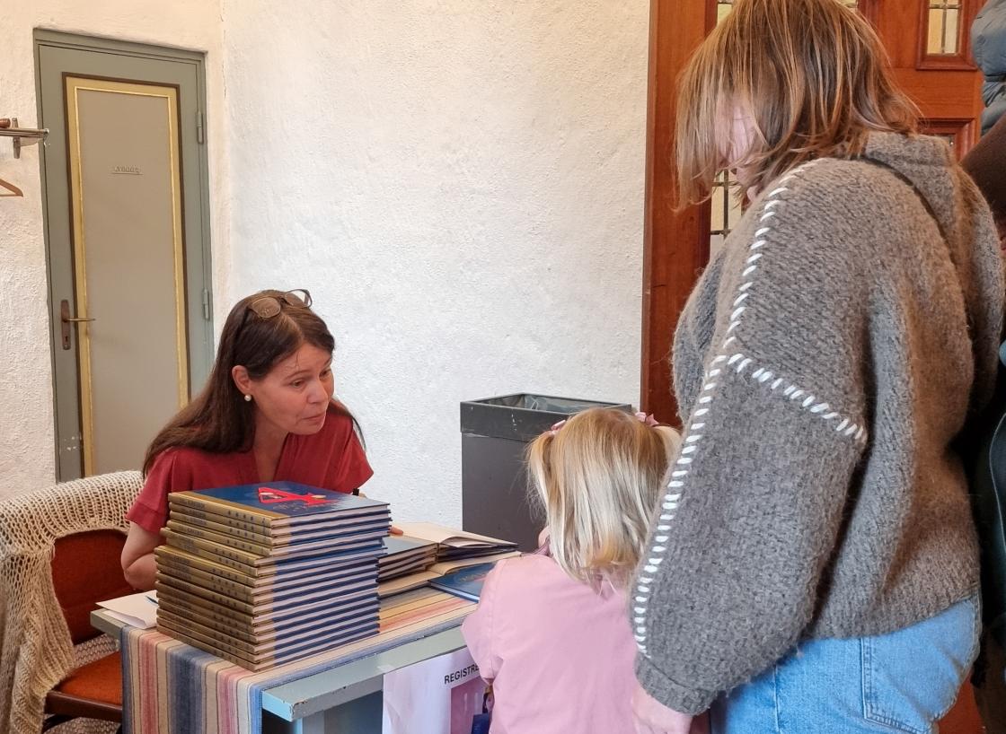 Menighetspedagog Lise Hagen skriver inn navnet til den nye eieren av 4 års boka