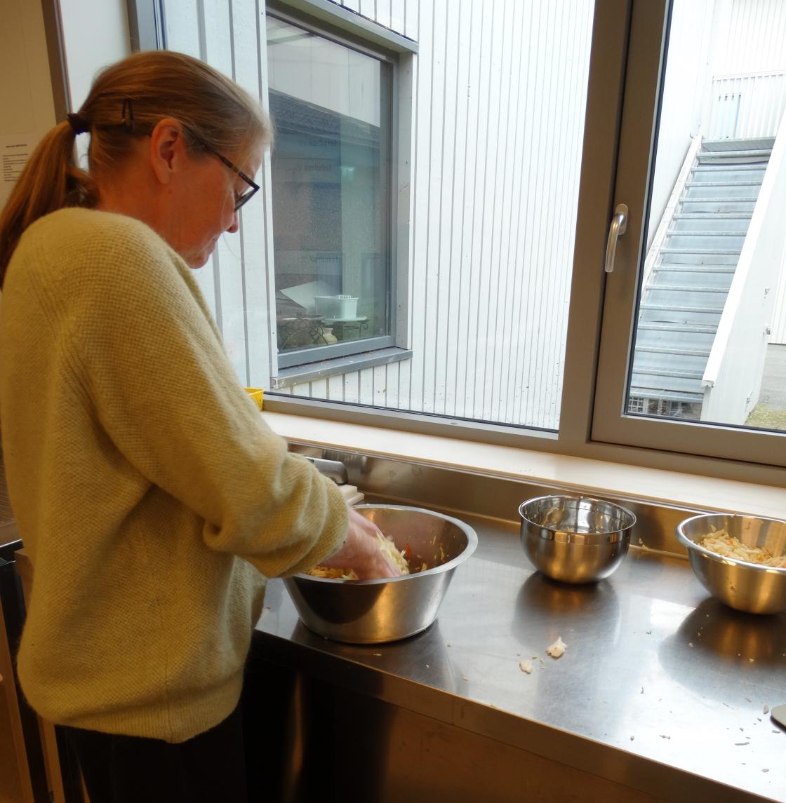 Kvinne moser kål og gulrot sammen med salt for fermentering