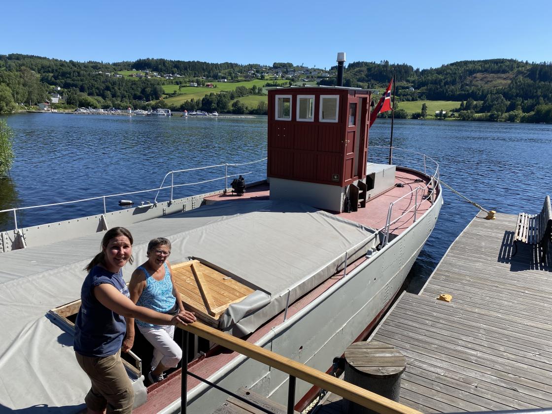 I juli 2024 var det åpen dag på MS Brandbu. Grethe Johnsrud fra Randsfjordsmuseet, til venstre,  ga info i sommersola til Ingeborg Rækstad og fotograf Inger Stensrud Haug.