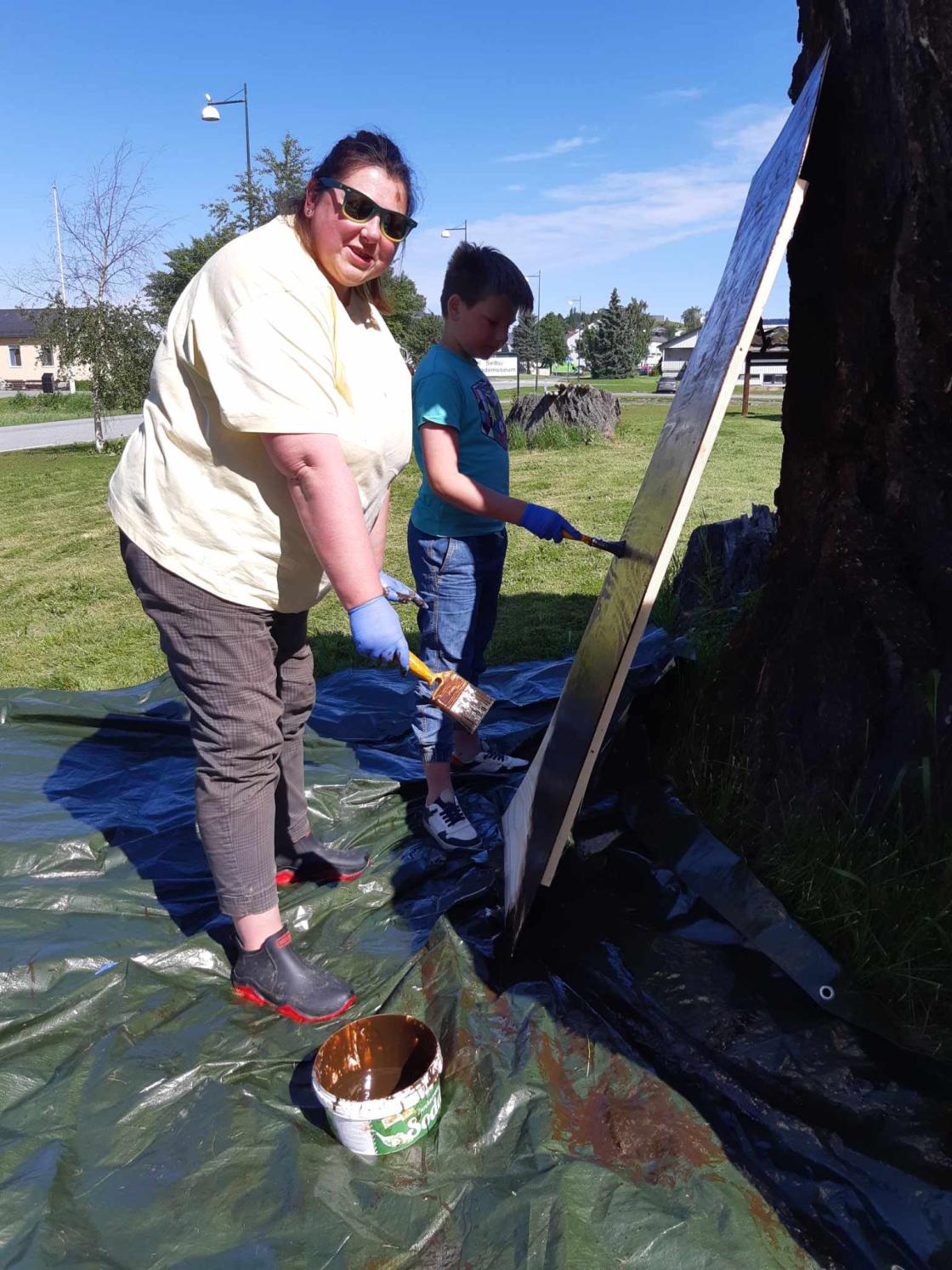 Mor og sønn på dugnad, maler/beiser benk