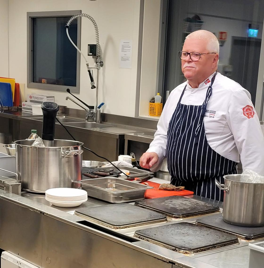 Kokk står bak kjøkkenøy og forklarer