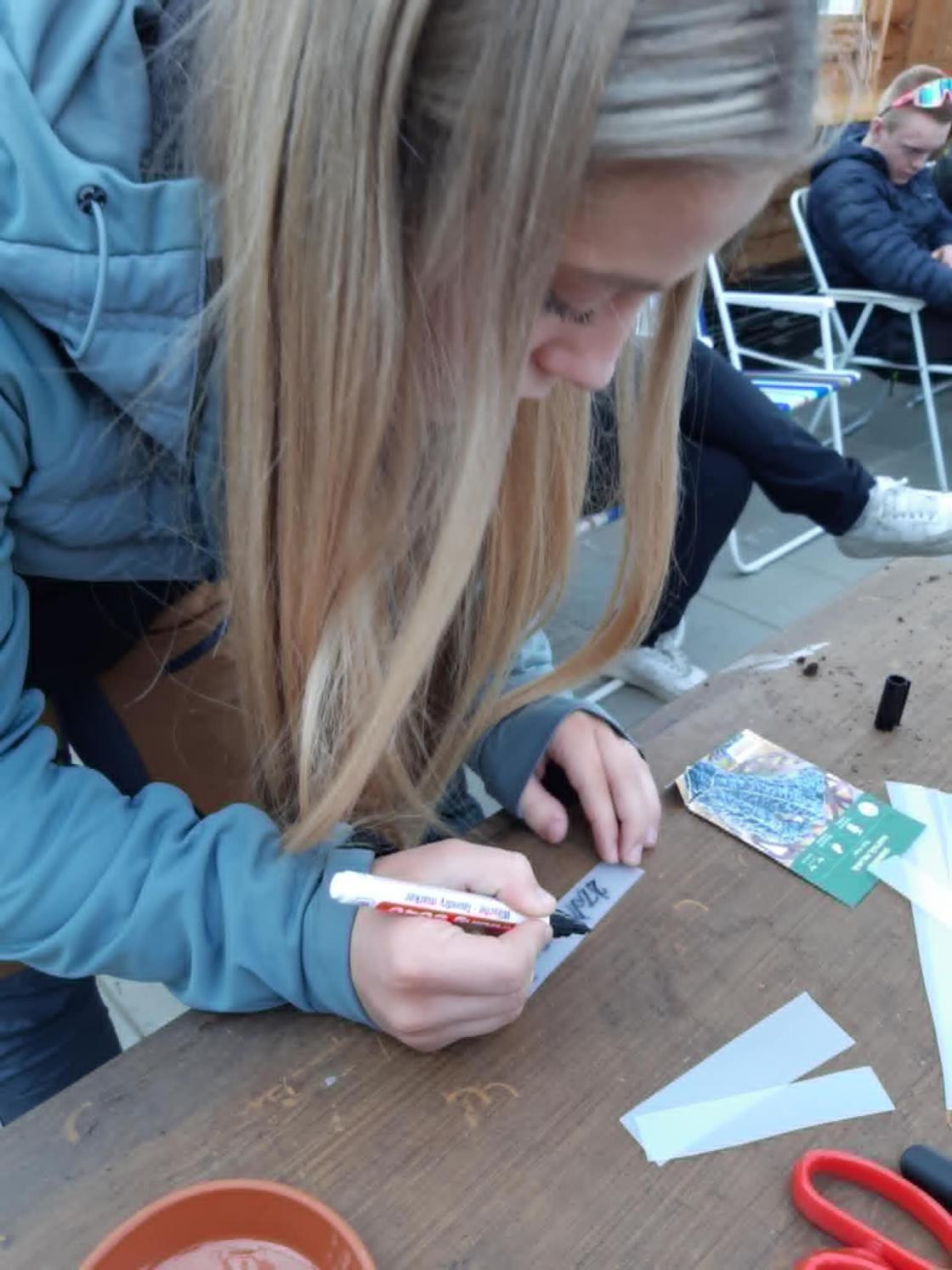 Jente skriver plantenavn på lapp, såing