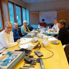 Bilete av damer rundt eit møtebord